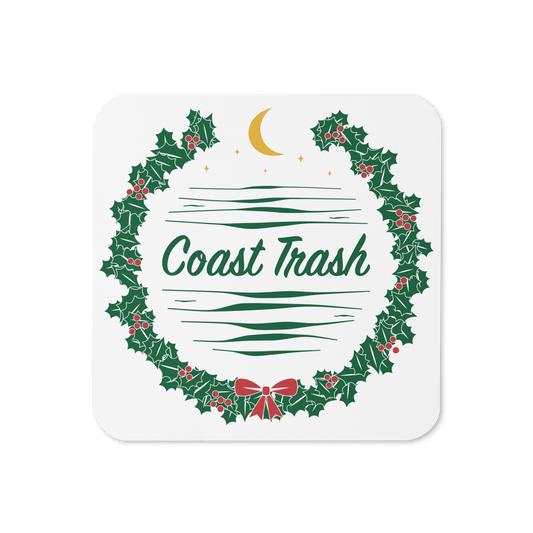 A Festive Contribution Coaster with a dense green Coast Trash holly wreath, red berries and a small red bow, gold crescent and stars, and coastal waves on a glossy white face.