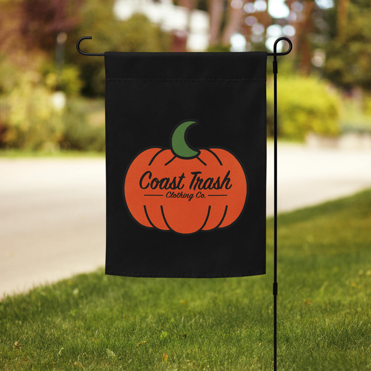 Double-sided Coast Trash Halloween garden flag with orange pumpkin displayed in a yard