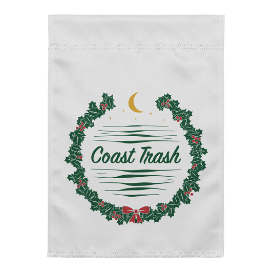 A Festive Contribution Garden Flag, front view. Original round holly wreath with single-line Coast Trash script, red berries and a small bow, gold crescent, stars, and coastal waves.